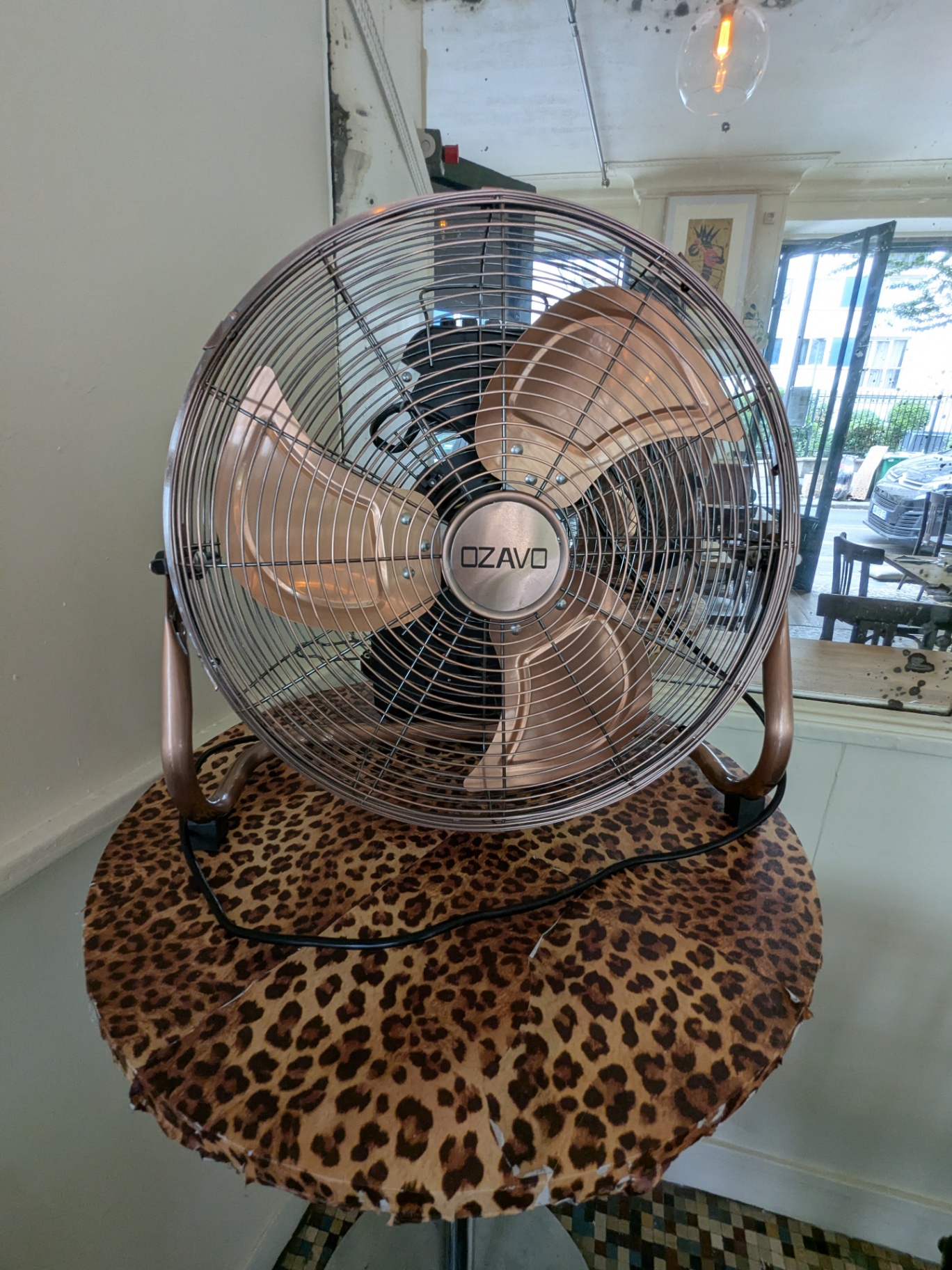 Ventilateur cuivré posé sur un tabouret léopard